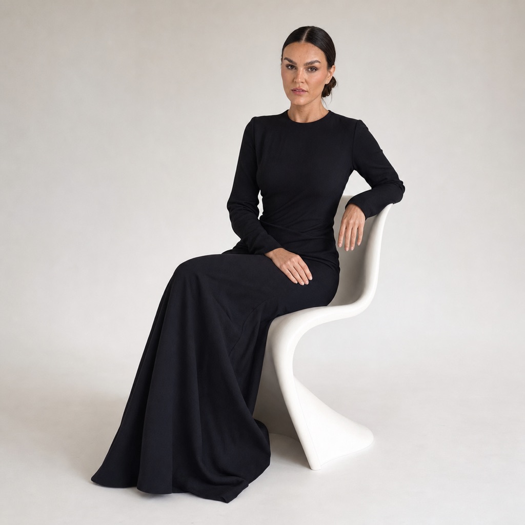 Sandra seated on a white sculptural chair in a black dress